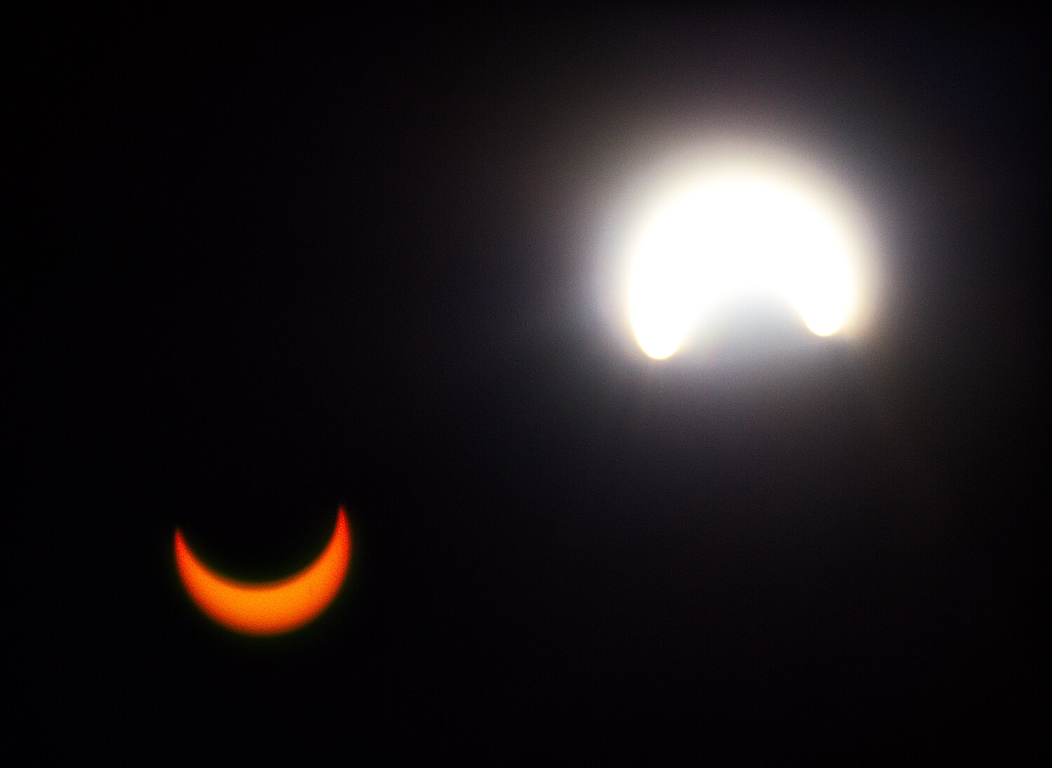 A lens flare (bottom-left) shows an inverted view of the sun, which shines brightly (top-right) as it emerges from behind the moon. [see some more sun shots]